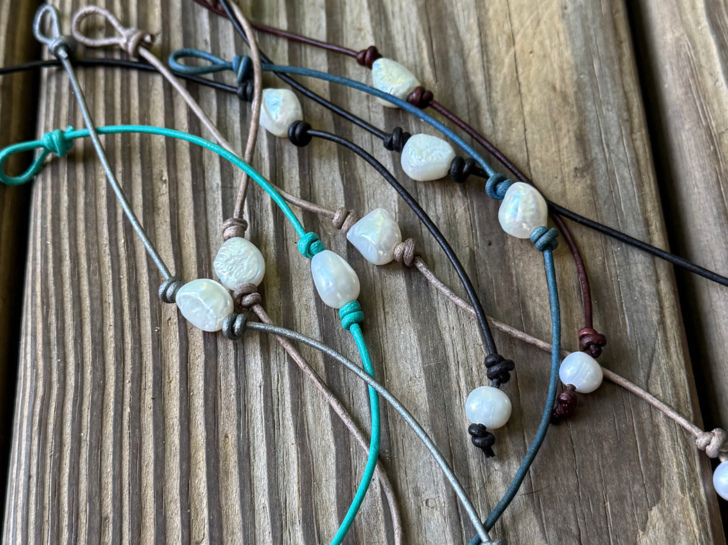 Set of beaded bracelets with pearls on a wooden surface