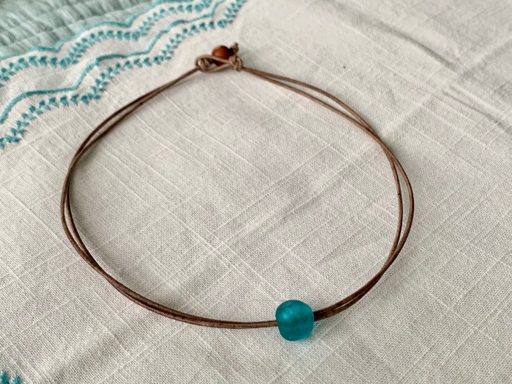 Double strand leather necklace with an aqua glass Ghana bead. toggle closure